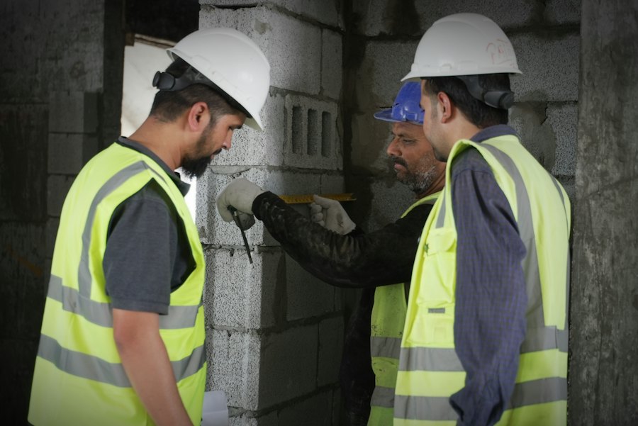 Three contractors in hi-vis vests and hard hats working together on site