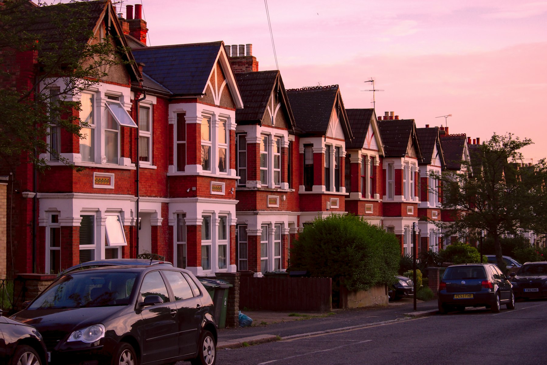 A row of red-brick terraced houses on an English street at dusk